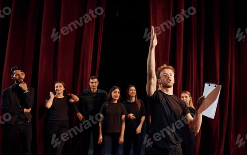 Preview: Group of actors in dark colored clothes on rehearsal in the theater