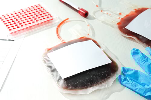 Preview: Bags and test tube with donor blood on light background, close up