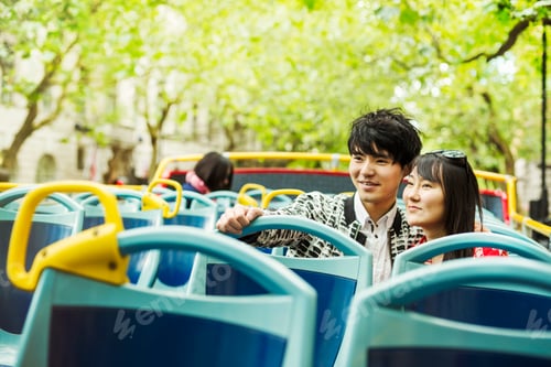 Preview: Smiling man and woman on the top of an open Double-Decker bus on a tour