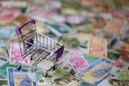 Preview: Supermarket trolley on many banknotes of different currency. Background of shopping worldwide