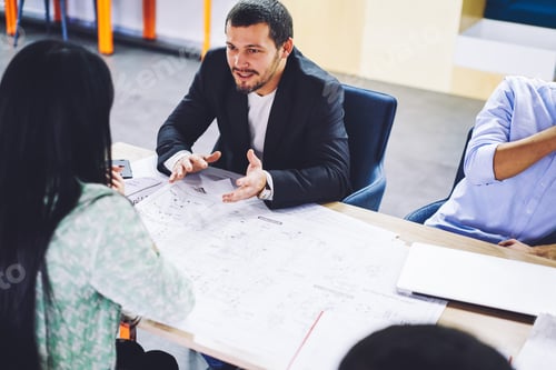 Preview: Experienced crew of architects brainstorming on sketches of project checking details together