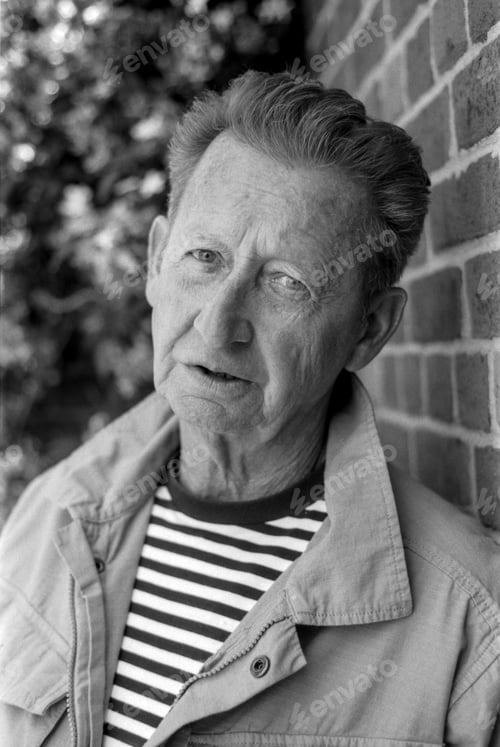 Preview: Senior man posing near brick wall in monochrome analog film photography