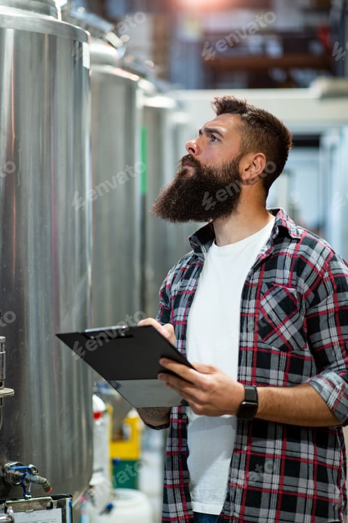 Preview: Man working in brewery and taking notes of the beer production