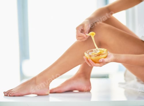 Preview: Cropped shot of an unrecognizable woman applying wax to her legs in the bathroom at home