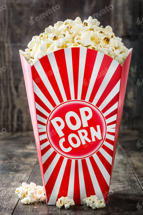 Preview: Popcorn overflowing from classic red and white striped cardboard box on wooden table