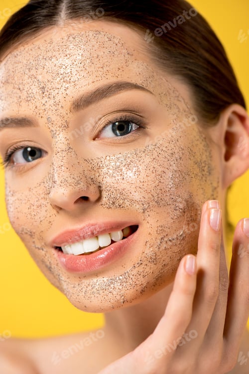 Preview: portrait of happy young woman applying peeling mask, isolated on yellow