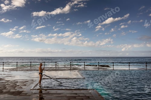 Preview: A serene moment by the ocean pool under a cloudspeckled sky.