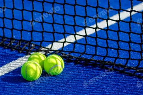 Preview: three ball near the net in a blue padel court, racket sports background concept