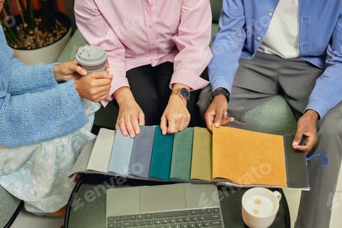 Preview: Hands of Interior Designers Choosing Color of Cloth on Fabric Samples while Working at Table Indoors