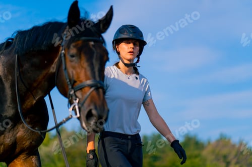 Preview: A helmeted rider leads her beautiful black horse by the harness in the riding arena horseback ride