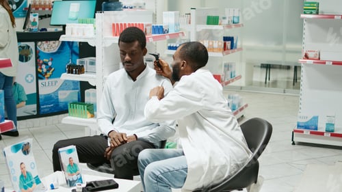 Preview: Health specialist consulting client with otoscope at clinic