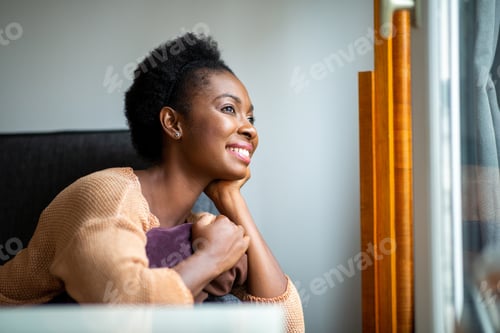Preview: Close up side of smiling young black woman looking out window