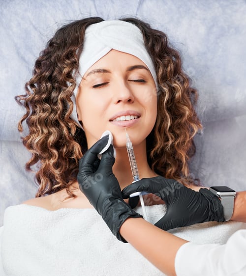 Preview: Cheerful young woman getting beauty injection in spa salon.