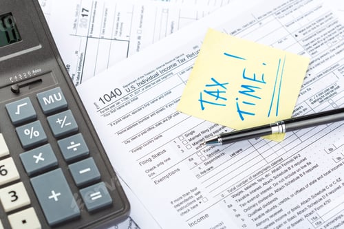 Preview: Tax return forms, calculator, and notes for tax preparation at a workspace during tax season