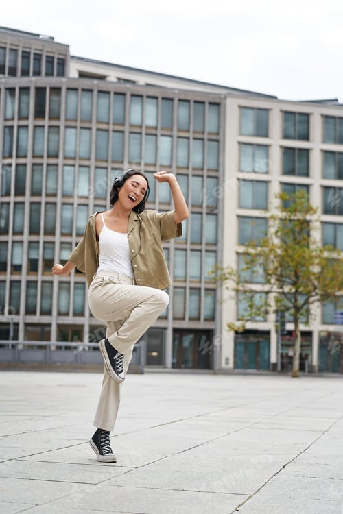 Preview: Vertical shot of dancing girl in headphones, listening music on street, enjoying sound in earphones