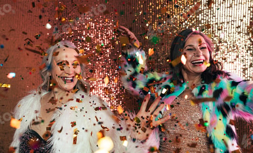 Preview: Senior females in fur coats celebrating together in studio under colorful confetti