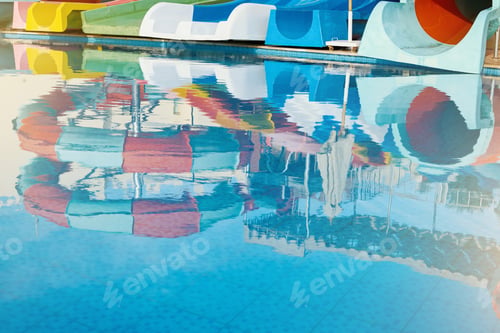 Preview: Reflection of water park with water colored flights in pool, slides, and pools at luxury hotel.