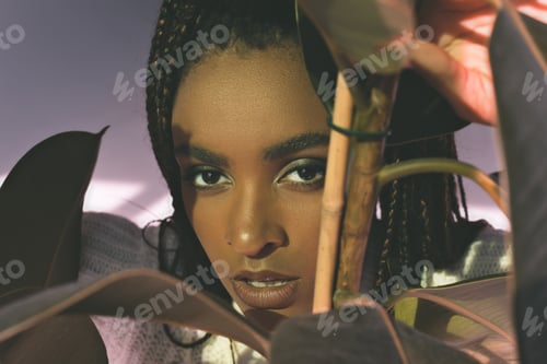 Preview: close-up portrait of beautiful african american girl looking at camera through leaves