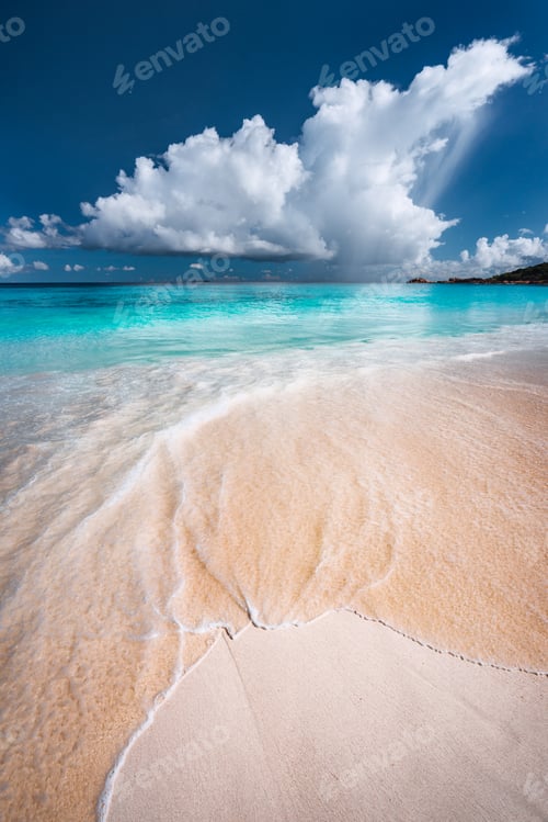 Preview: Ocean wave rolling towards tropical sandy beach. Turquoise blue ocean in background with white