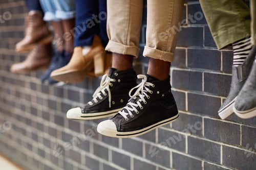 Preview: Closeup shot of an unidentifiable group of university students sitting together on a wall outside