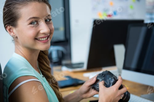 Preview: Smiling woman holding DSLR camera at wooden desk in office, with computer monitors, copy space