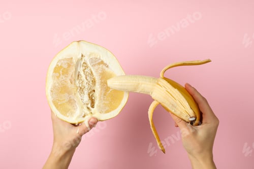 Preview: Female hands hold banana and pomelo with condensed milk on pink background