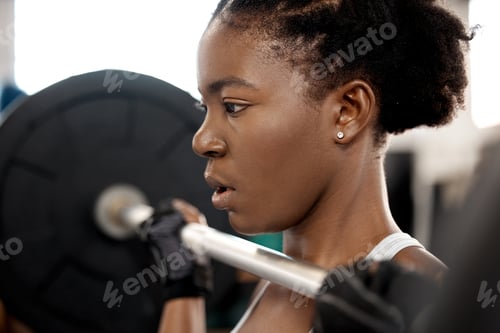 Preview: Feel weak Think strong. Shot of a sporty young woman exercising with a barbell in a gym.