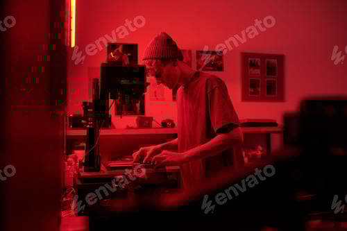 Preview: Teen Boy in Darkroom Developing Photo Prints in Red Light