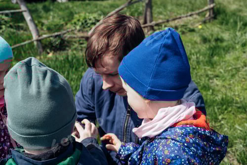 Visualização: O pai mostra às crianças um lagarto que ele pegou na grama.