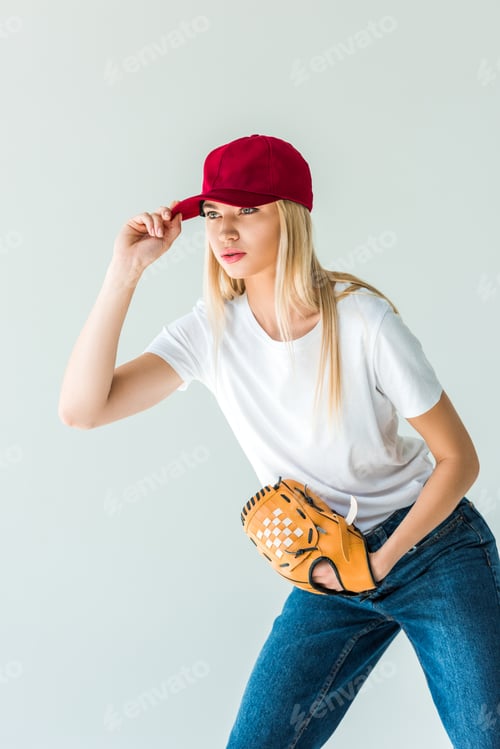 Preview: attractive baseball player touching red cap and holding baseball glove isolated on white