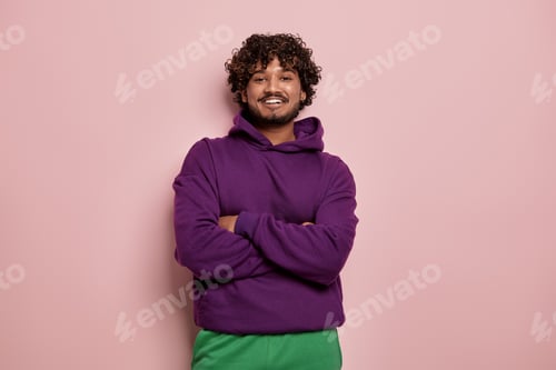 Preview: Fashionable young Indian man looking at camera and smiling against pink background