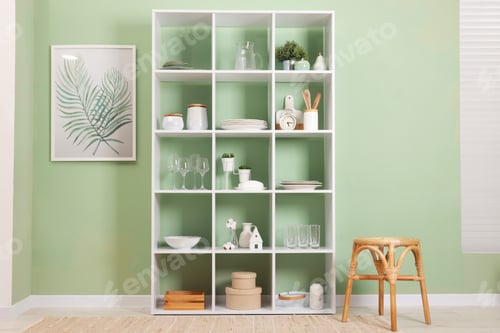 Preview: Shelving unit with dishware near olive wall indoors