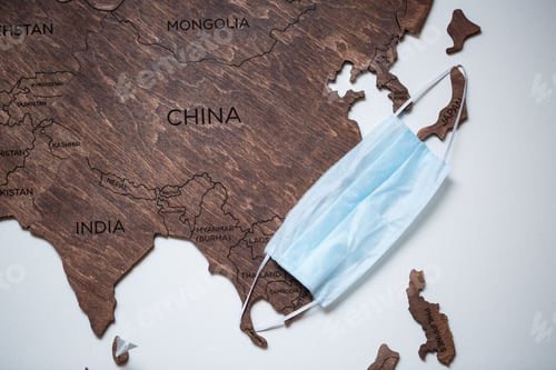 Preview: wooden map on a white background with a medical mask for protection against the virus