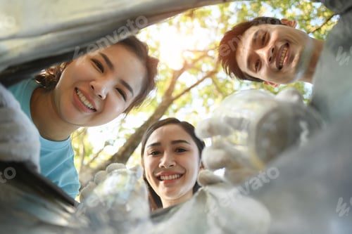 Preview: Young volunteer putting plastic bottles in a trash bag. The view from the bag
