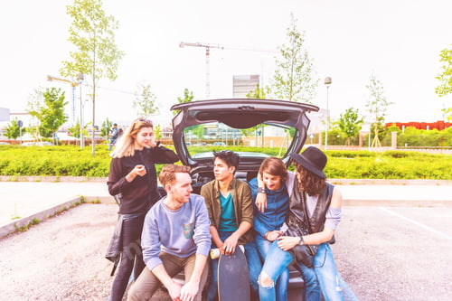 Preview: young multiethnic friends sitting in a trunk