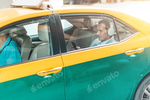 Preview: On his way. Businessman with headphones rides in a taxi. Copy space in lower part