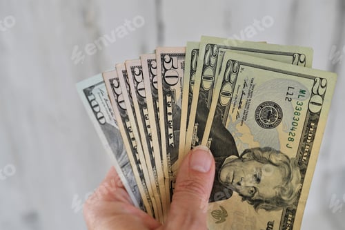 Preview: A female holds a handful of money, currency, cash, salary, extra income, side hustle, earnings