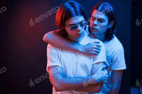Preview: People's unity. Portrait of twin brothers. Studio shot in dark studio with neon light