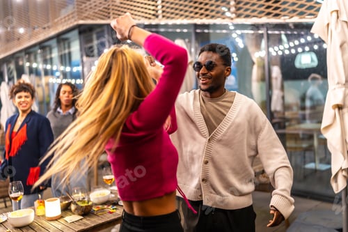 Preview: Multi-ethnic friends dancing together at outdoors terrace at night bar