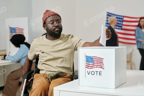 Preview: African American young man with disability putting ballot paper into box