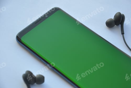 Preview: Low angle view of curved screen mobile phone with green screen and black color earphone