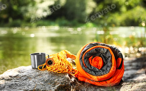 Preview: Rolled sleeping bag and other camping gear near lake