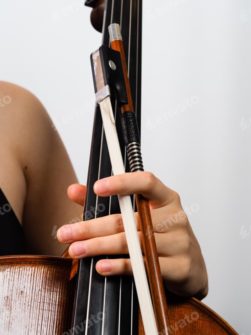 Preview: young female woman musician hold handmade classical cello in her hands over a solid background