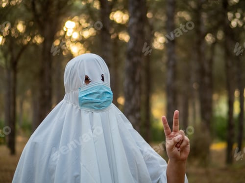 Preview: Shallow focus shot of a man dressed like a bedsheet ghost, also wearing a facemask