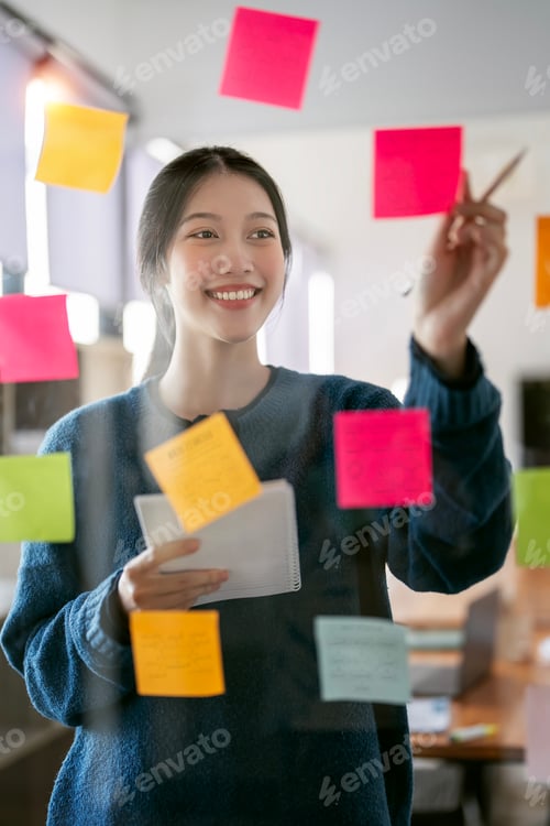Preview: businesswoman using post it notes in glass wall to writing strategy business plan to success