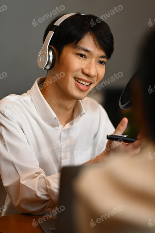 Preview: Smiling radio host wearing headphone and recording voice over radio interview guest conversation.
