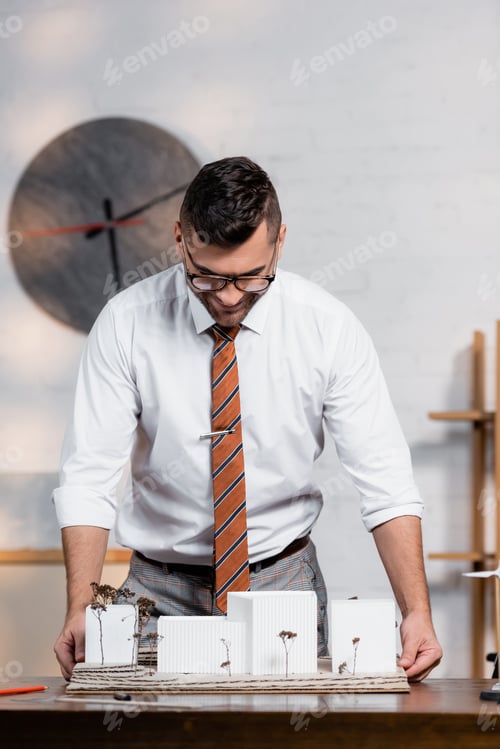 Preview: smiling architect looking at architectural project in office