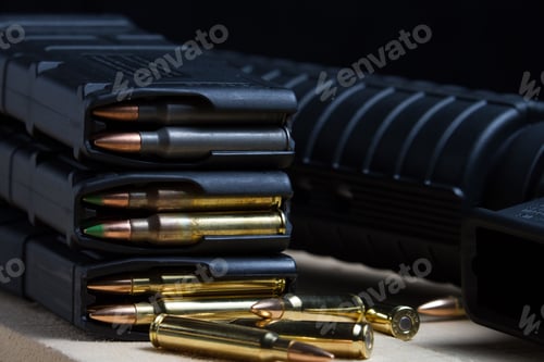 Preview: 223 rifle ammunition bullets in a loaded mag arranged in front of an AR-15 rifle