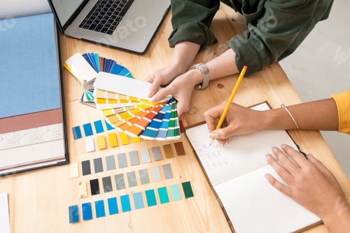 Preview: One of female designers holding color palette while her colleague making notes