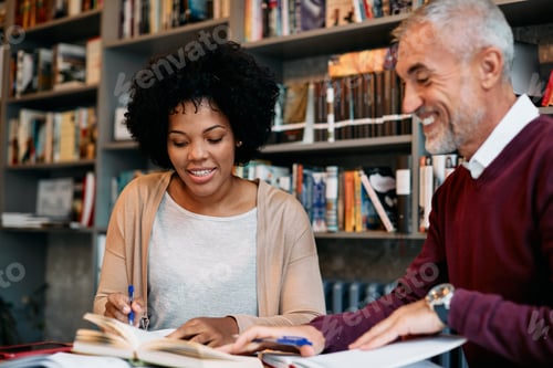 Preview: Happy mid adult black student and her mature friend learning in a library together.